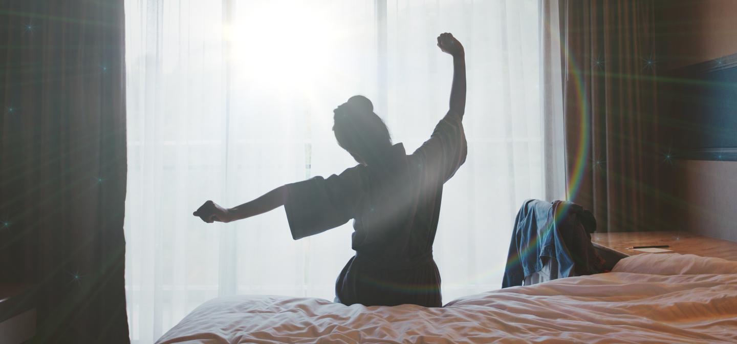 Woman stretching by a sunlit window, symbolizing renewal and emotional well-being.