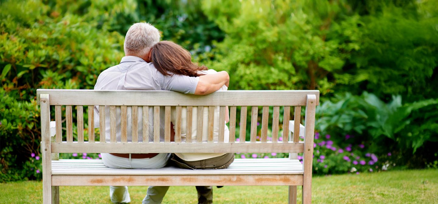 Couple sitting on a bench embracing in nature, symbolizing emotional healing and renewed intimacy after heartbreak.