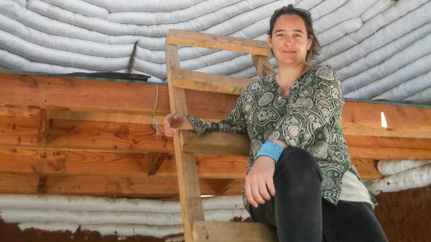 ELIP Alumna Maria Loreto Retamales sitting in front of a SuperAdobe wall