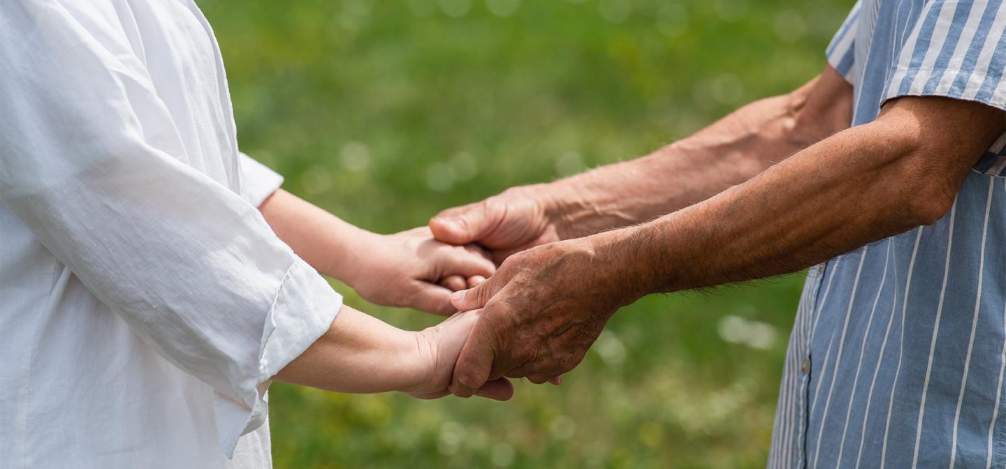 Two people holding hands outdoors, symbolizing family connection, support, and healing.