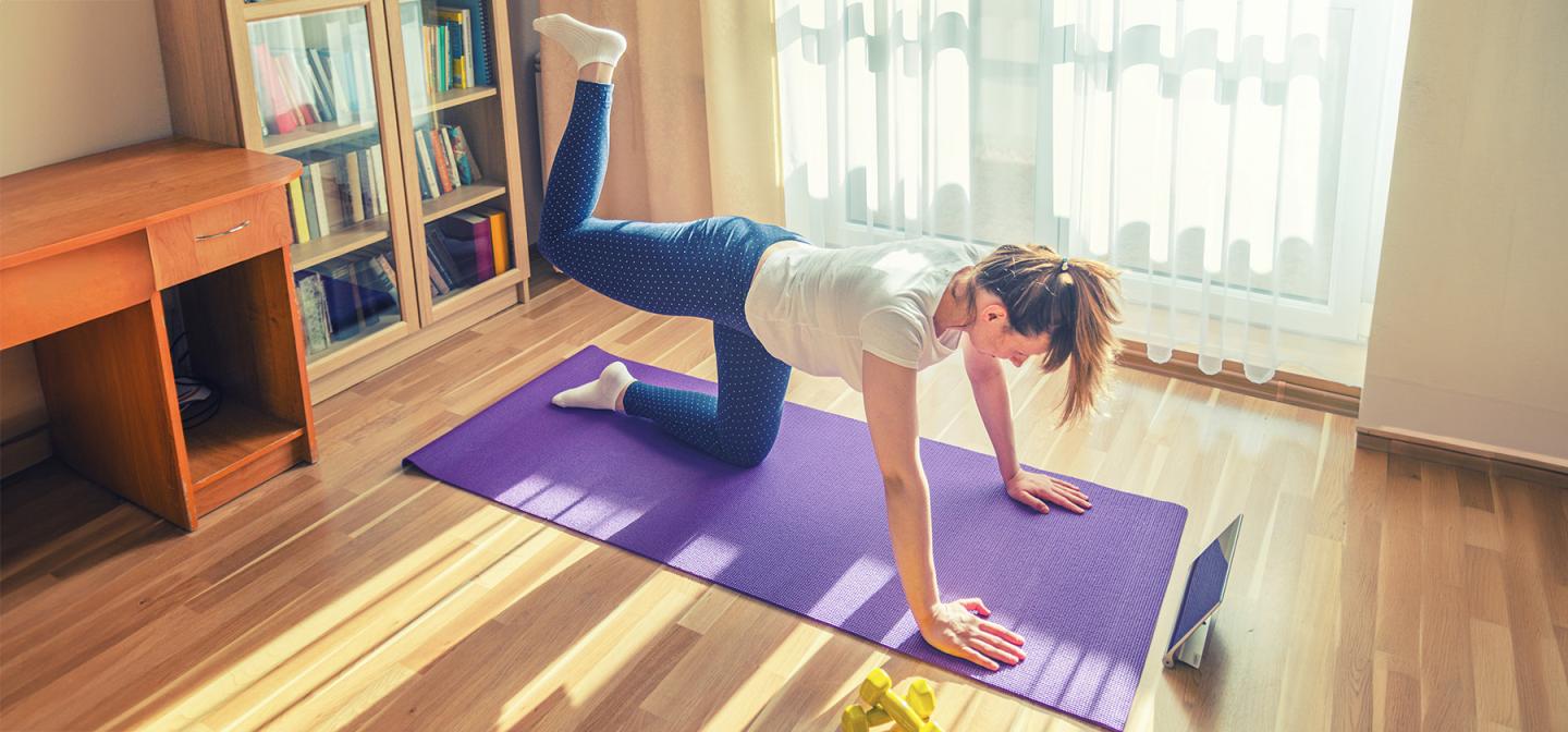 Woman performing a glute activation exercise (donkey kicks) on a yoga mat to strengthen glutes and support back and knee health