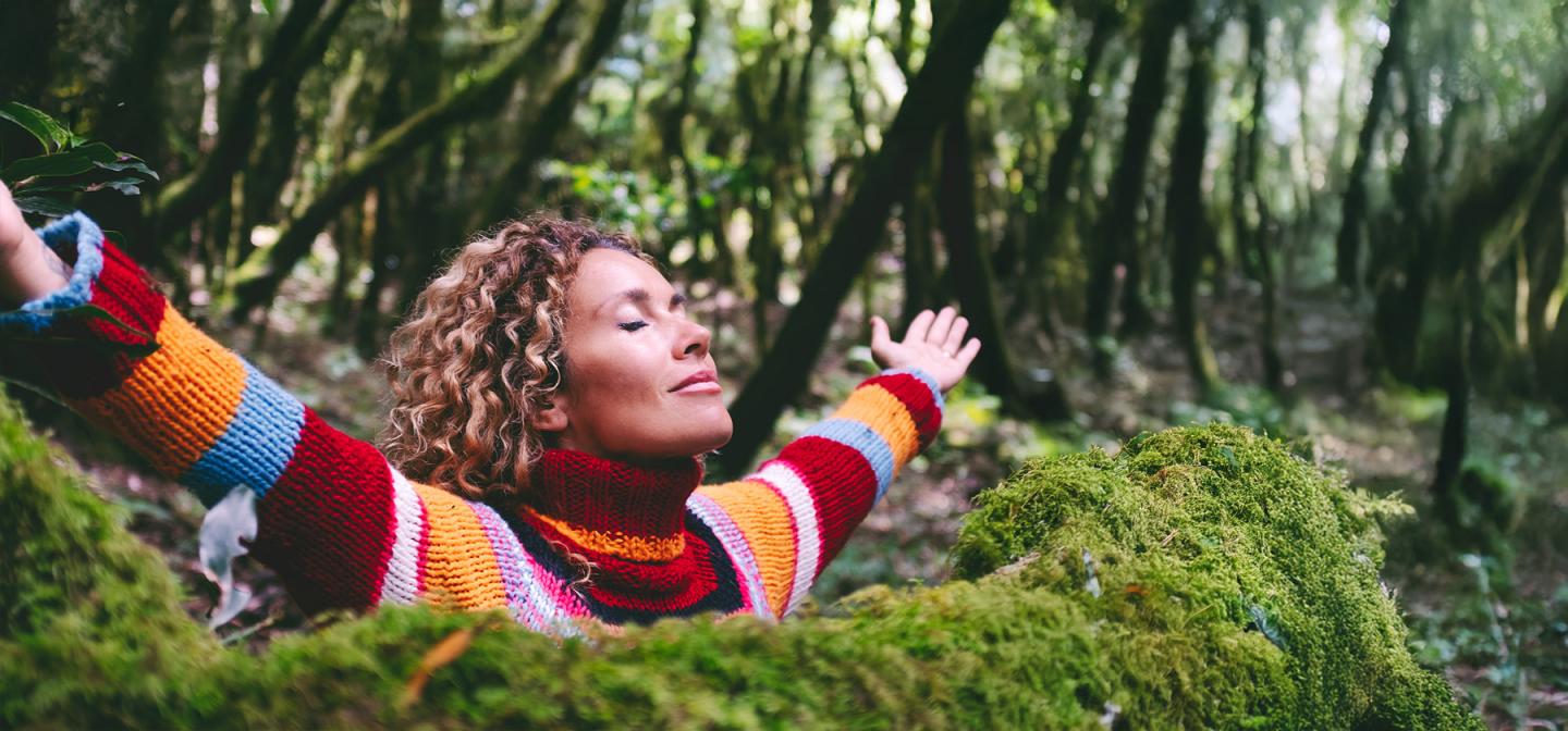 Woman breathing deeply in the woods on a health & wellness retreat