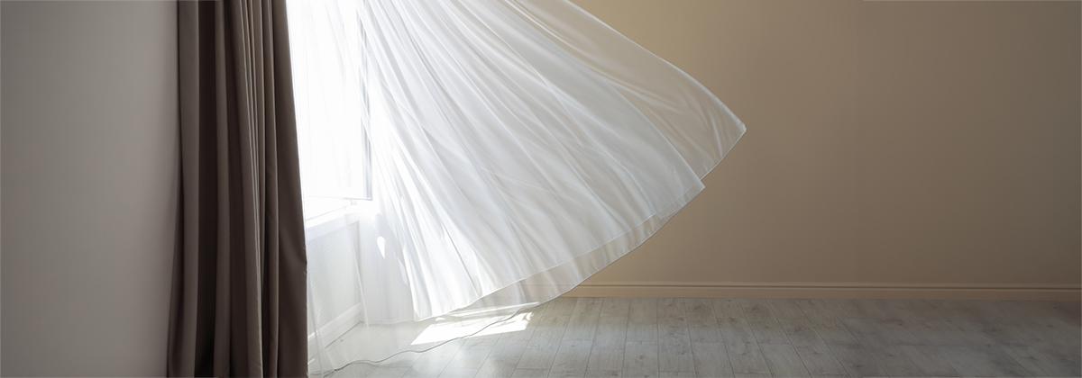 Curtain blowing in the breeze with dramatic light coming through, showing intuition in day-to-day life.