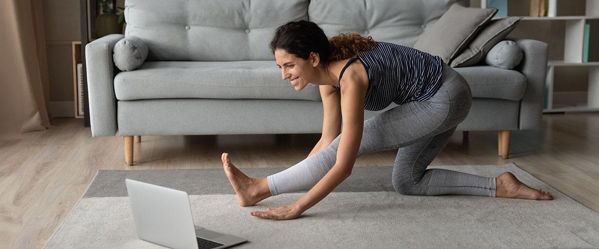 Woman doing yoga in front of a laptop.