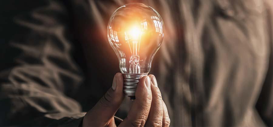 Person holding a glowing light bulb, symbolizing inner magic, personal power, and the spark of transformation explored in 'Magic is Power'.