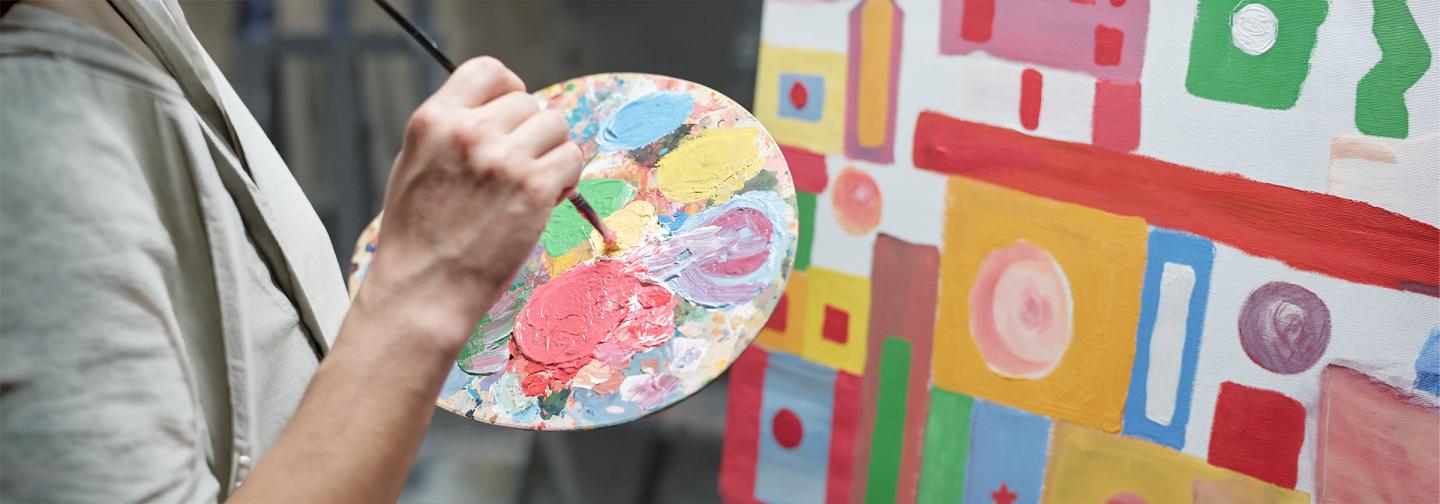 Person painting a colorful abstract canvas, illustrating the mental health benefits of creativity, stress relief, and art-making.