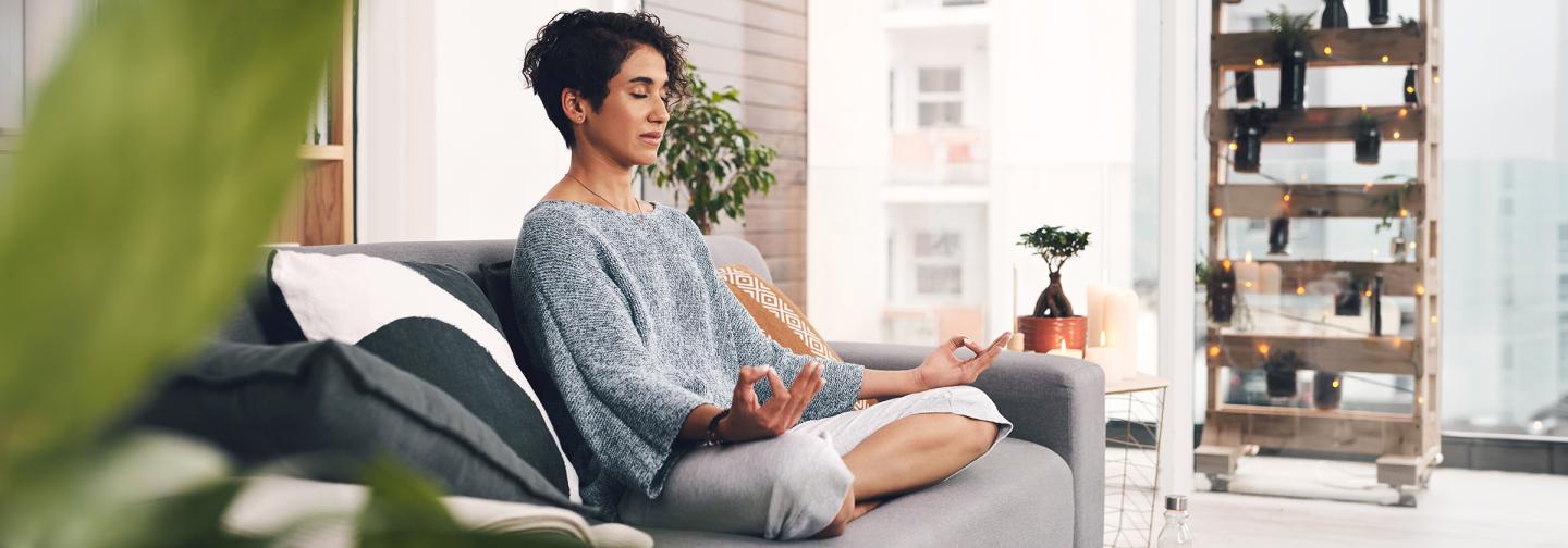Woman practicing mindfulness meditation at home to support resilience, self-care, and stress reduction.