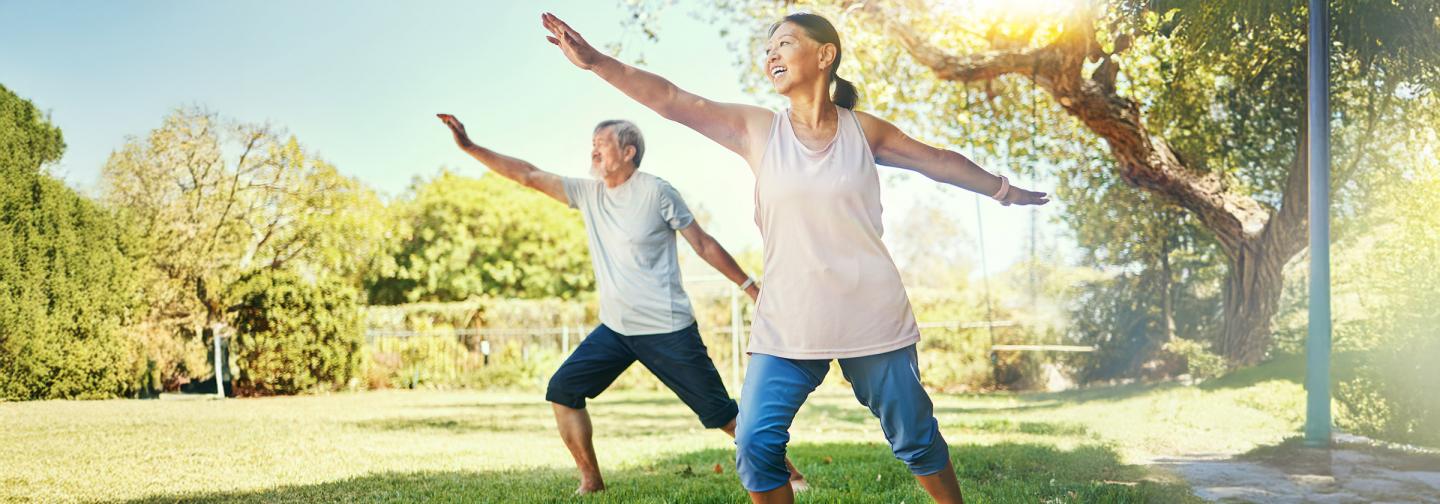 Seniors practicing tai chi balance exercises in a park for fall prevention and healthy aging.