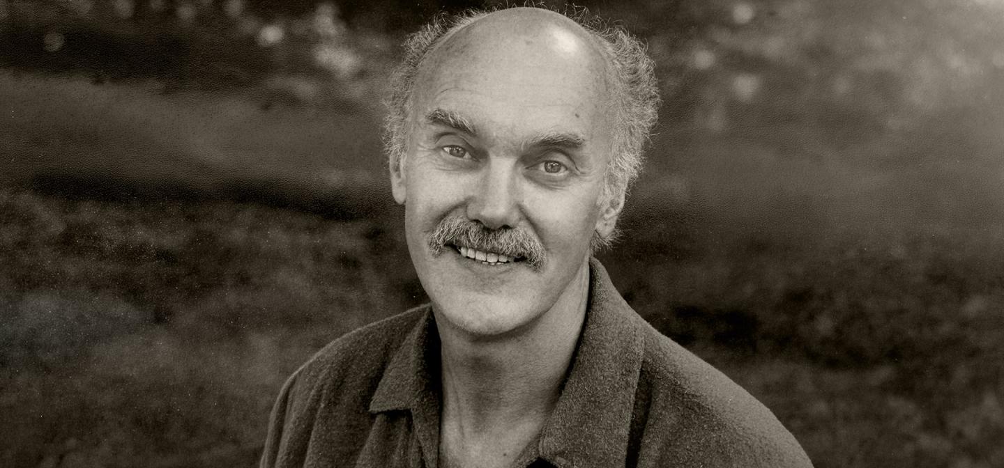 Black-and-white portrait of spiritual teacher Ram Dass smiling outdoors