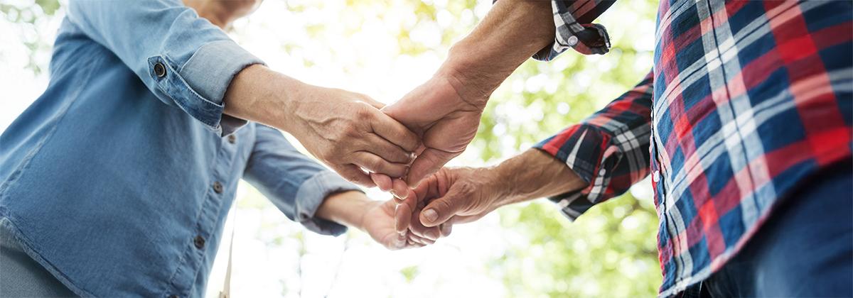 Couple holding hands in a circle, symbolizing connection and healing in family and relationship workshops at Omega Institute.