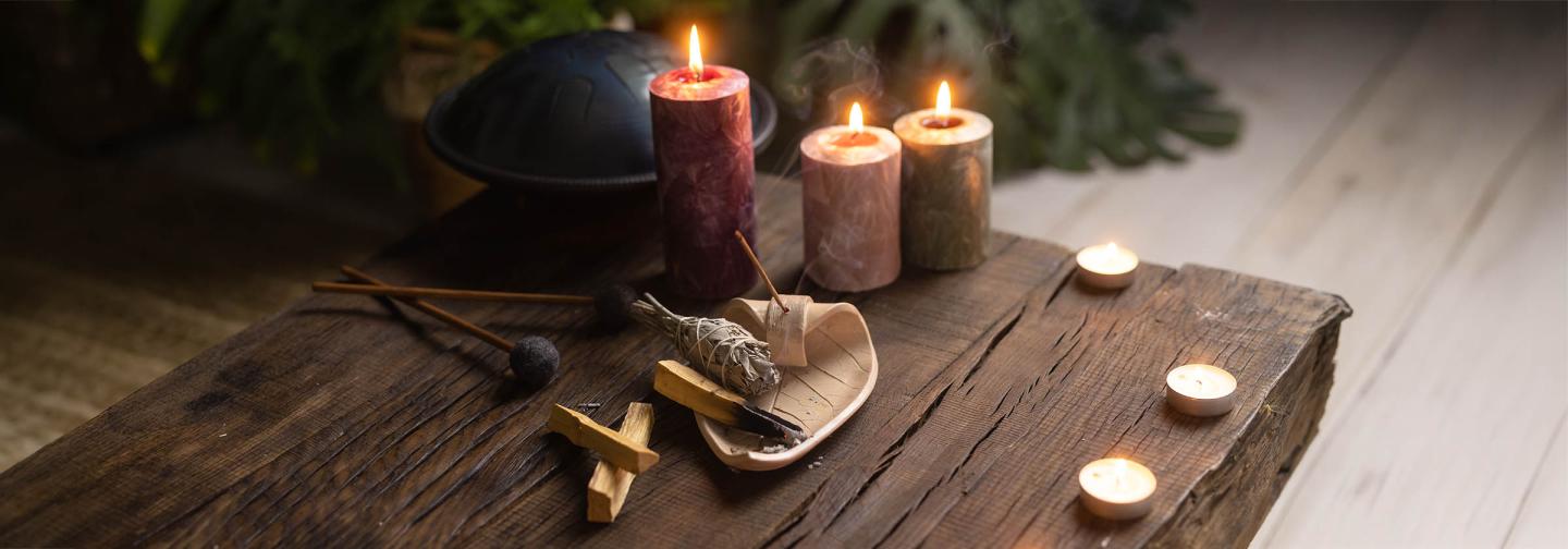 Sacred ritual altar with lit candles, smudging herbs, incense, and ceremonial tools arranged for meditation, spiritual practice, and healing retreat.