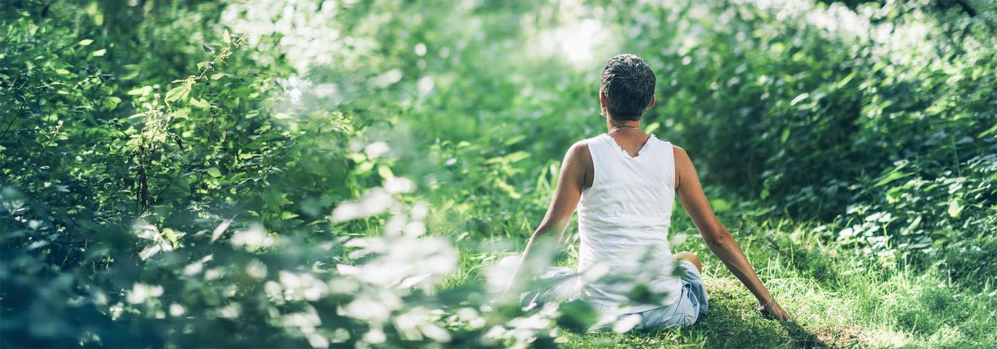 Woman meditating in a field, as part of a Supercharged Wellness energy healing workshop