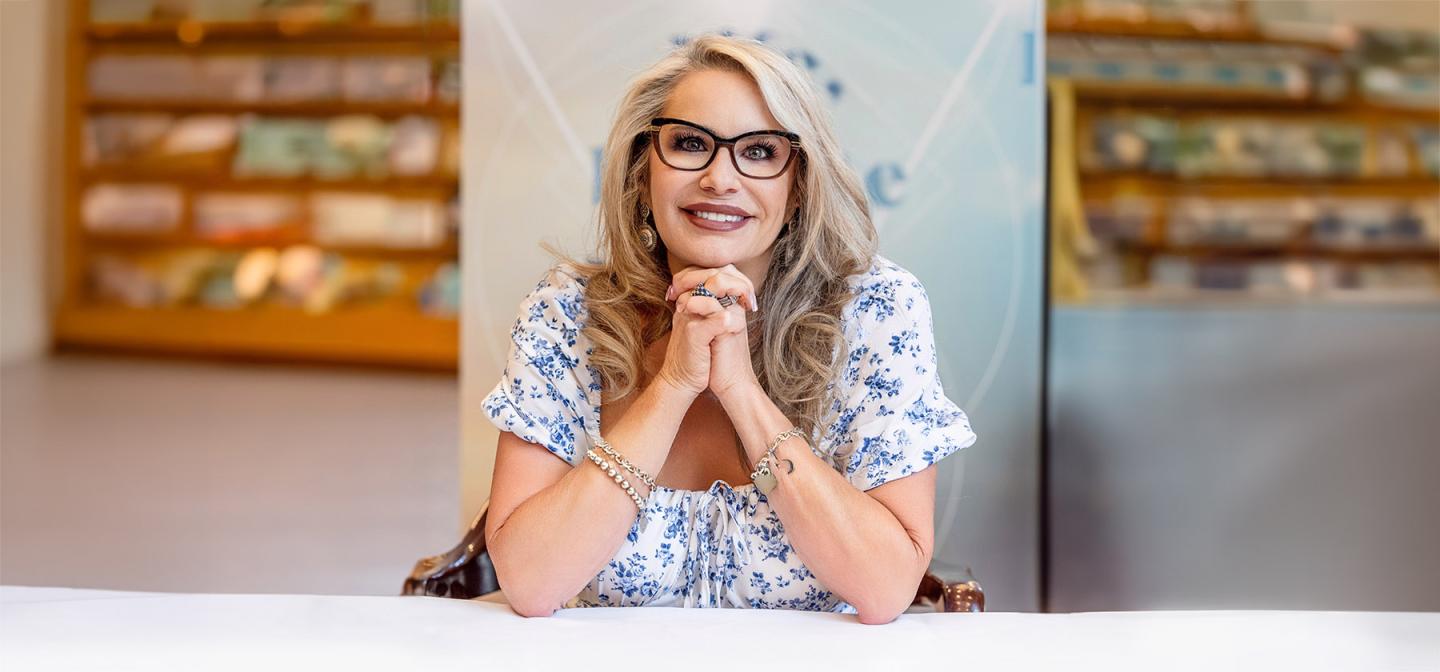 Spiritual medium Susan Grau smiling, seated with hands clasped.