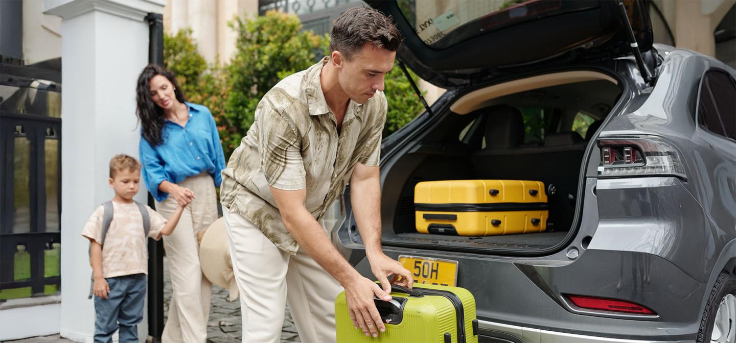 A father packing suitcases into a car while a mother and child stand nearby, illustrating themes of attachment, family roles, and authenticity.