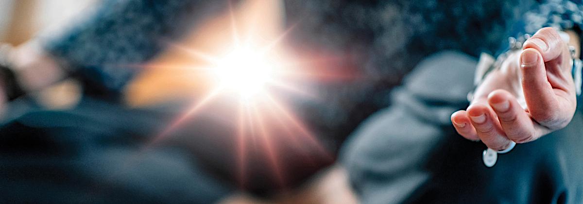 Woman sitting in lotus pose with thumbs and forefingers touching and ray of light, signifying motional healing and spiritual transformation.