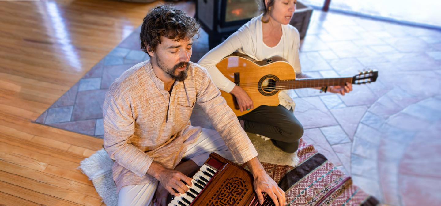 Man and woman playing guitar and harmonium