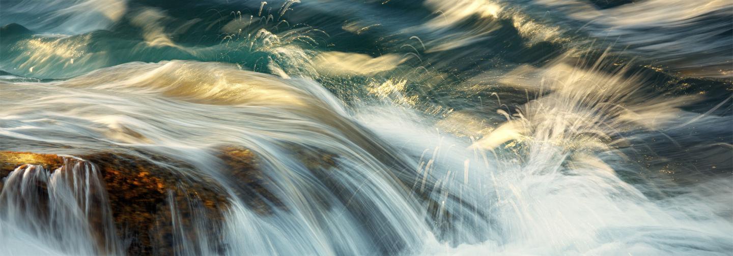 Ocean waves flowing over rocks, illustrating the movement of water, connection, and the embodied practice of belonging in nature.