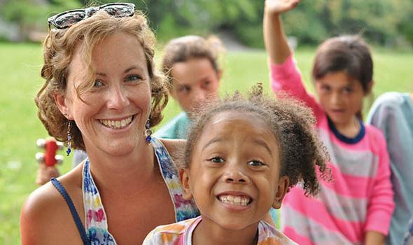 Woman and daughter with smiling kids behind