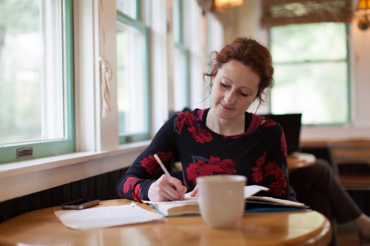 Woman writing with a cup of coffee