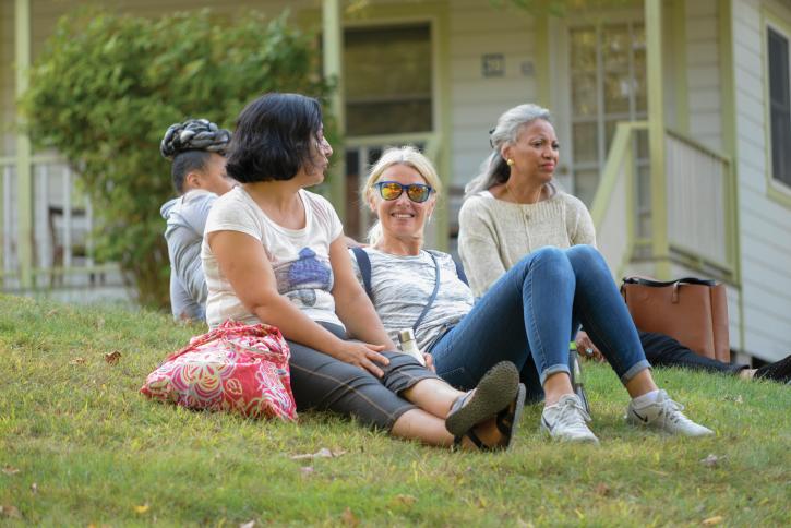 Women conference participants sit outside and chat together