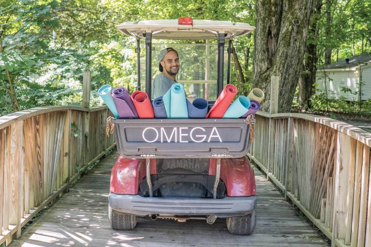 Smiling man driving a golf cart filled with brightly colored yoga mats
