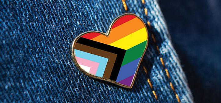Progress Pride Flag heart pin on denim jacket representing LGBTQ+ inclusion, diversity, and Pride Weekend at Omega Institute.