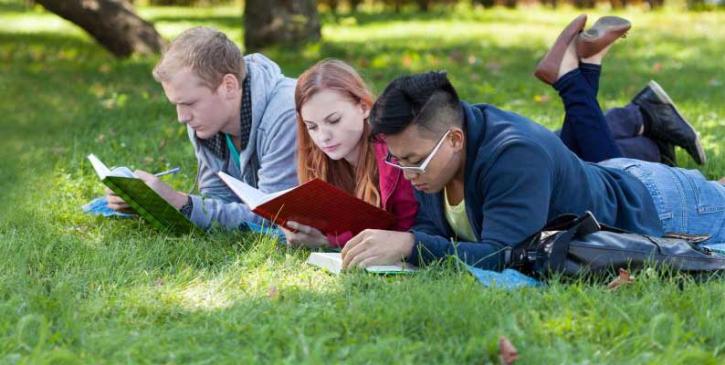 3 young people reading together outdoors