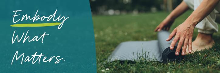 Embody What Matters. Person rolling out a yoga mat in the grass